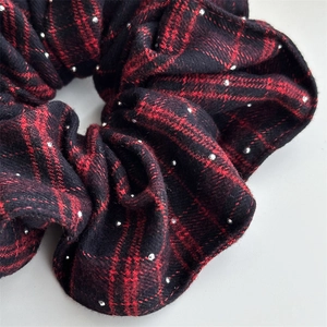 Detailed close-up of red tartan scrunchie with sparkling silver rhinestone accents