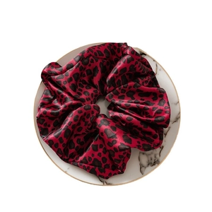 Chouchou en satin à motif léopard rouge et noir sur une assiette en marbre