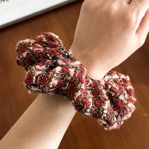 Détail d'un chouchou en tweed rouge et noir avec fils métalliques au poignet