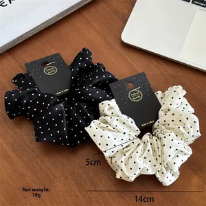 Close-up of black and white polka dot scrunchies with 14cm diameter and 5cm width detail