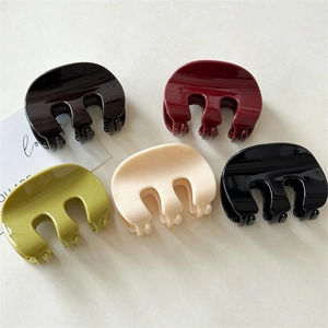 Detail of five glossy M-shaped shark hair claws in brown, red, green, cream, and black