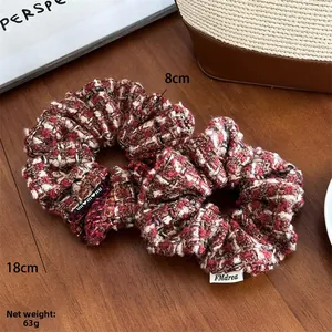 Détail de chouchous en tweed rouge et noir montrant la texture tissée et les dimensions