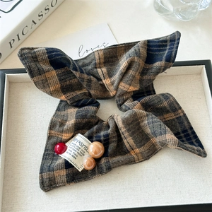 Detail of red plaid scrunchie with decorative beads and Happy & Smile fabric label