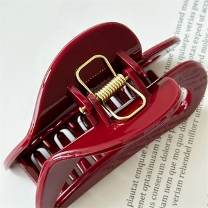 Detail of burgundy heart hair claw clip with golden metal spring on magazine page