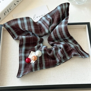 Detail of vintage plaid scrunchie with colorful beads and fabric label on a tray