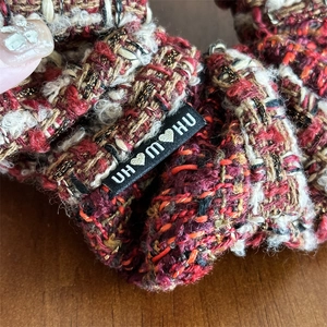Détail d'un chouchou vintage en tweed rouge avec fils dorés et étiquette de marque tissée