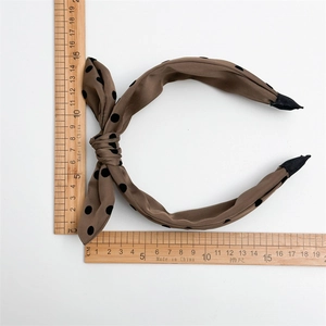Detailed top view of a brown polka dot headband with measurement ruler on white background