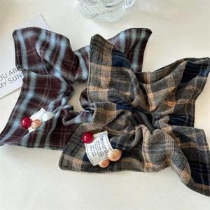 Detail of plaid scrunchie with blue-brown check fabric and vintage label decoration