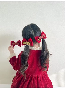 Detail of red velvet bow hair clips with Chinese New Year greetings and gold glitter accents