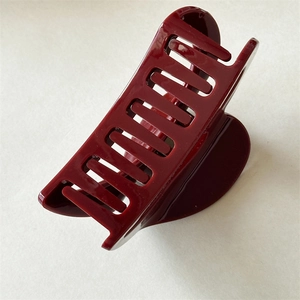 Close-up of a glossy deep red French vintage hollow heart hair claw clip on white surface