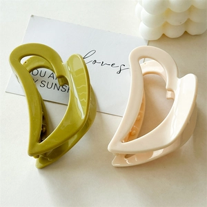 Detail of olive green and cream hollow heart hair claws with a glossy finish