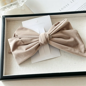 Detailed macro shot of a beige velvet bow hair clip on a white jewelry display card