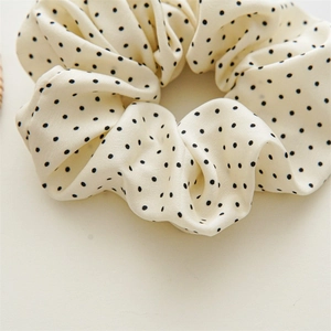 Close-up of elegant cream polka dot chiffon scrunchie showing fabric texture and detail