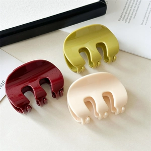 Close-up of elegant wide-tooth hair claws in wine red, olive green, and cream colors