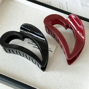 Detail showing large heart-shaped hair claws in glossy black and wine red resin finish