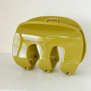 Macro detail of French style M-shape shark hair claw clip in olive green resin