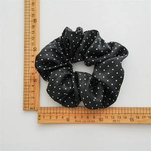 Detail shot of a black and white polka dot satin scrunchie showing a diameter of 11cm