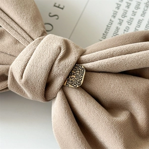 Macro detail of velvet bow hair clip with engraved gold square metal buckle
