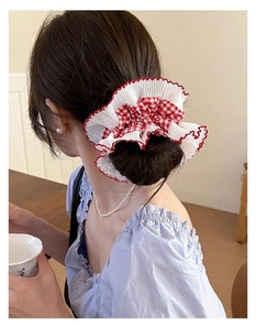 Detailed shot of a red plaid scrunchie with lace edge worn on a bun hair style