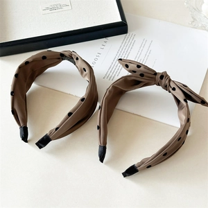 Detail of coffee brown polka dot headbands in knotted and bow styles on a desk