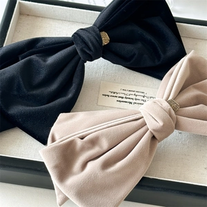 Detailed macro view of black velvet bow hair clip with gold metal buckle and soft texture