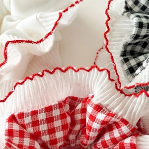 Detail of red and white checkered fabric hair scrunchie with delicate scalloped edges