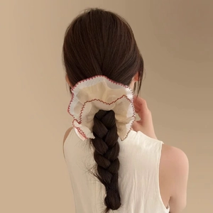 Détail d'un grand chouchou en dentelle beige avec bordure contrastée et volants doux