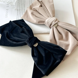 Close-up of elegant velvet bow hair clips in black and beige with gold heart details