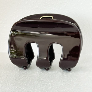 Detailed close-up of dark brown M-shaped shark clip with a glossy resin finish