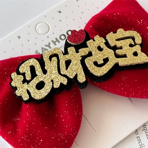 Detailed macro view of red velvet bow hair clip with gold glitter lettering for children