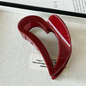 Close-up of red heart-shaped hollow hair claw clip with a glossy finish on white surface