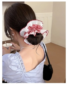 Macro view of large red checkered scrunchie with white ruffled edges on a bun