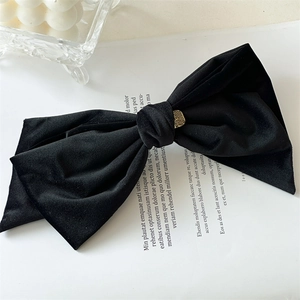 Detail of a large black velvet bow hair clip with a gold metal decorative buckle