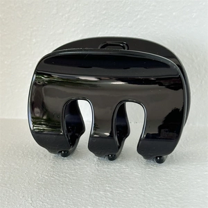 Close-up of a minimalist black gloss hair claw clip with a sleek M-shaped design