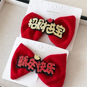 Close-up of red velvet bow hair clips with gold glitter New Year festive calligraphy