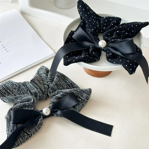 Detailed macro view of luxury fabric scrunchies with satin bows and pearl embellishments