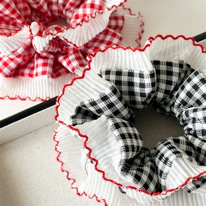 Detailed close-up of red and black plaid scrunchies with white pleated lace edges