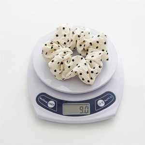 Detailed view of polka dot scrunchie on electronic scale showing 9.0g weight