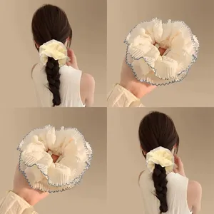 Détail d'un chouchou en dentelle crème avec bords ondulés bleu marine sous plusieurs angles
