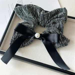Detail shot of black scrunchie with silver silk texture, satin bow, and centered pearl bead