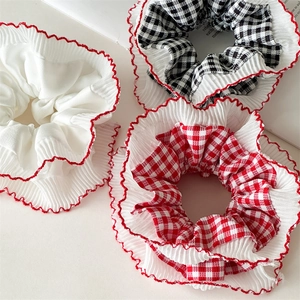 Detailed view of three chiffon scrunchies with red lace edges in plaid and white