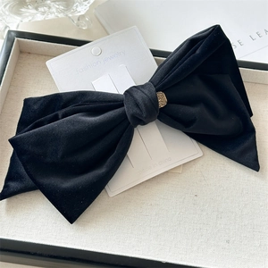 Detail of black velvet bow hair clip with gold metal buckle on jewelry card