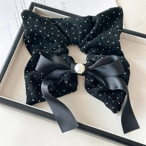 Detail of black bow hair tie with silver sparkles and a central faux pearl accent