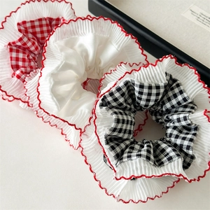 Detail of red plaid scrunchies with white chiffon pleats and red ruffle stitching accents