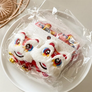 Détail de pinces à cheveux en peluche Lion Dance avec pompons rouges et cloches d'or