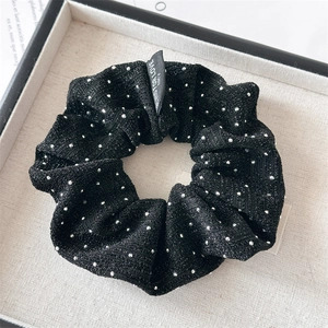 Detailed close-up of a black shimmering scrunchie with a Blind for Love textile label
