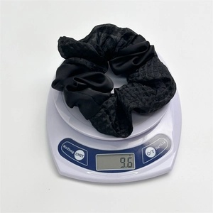 Detail showing high-elasticity black satin hair scrunchie weighing 9.6g on a digital scale