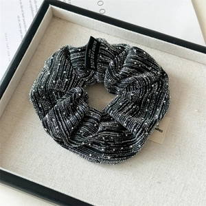 Detail of glitter fabric scrunchie with vertical stripes and Blind For Love label