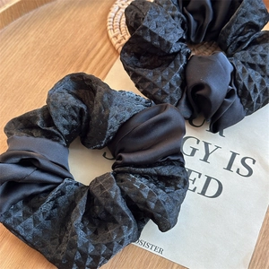 Detail of premium black satin and mesh scrunchie featuring elegant diamond pattern textures