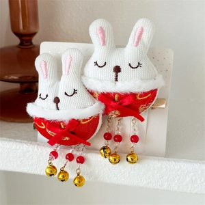 Détail de pinces à cheveux lapin avec pompons rouges et cloches dorées pour le Nouvel An